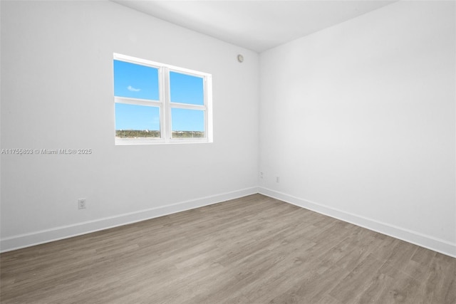 spare room featuring baseboards and wood finished floors