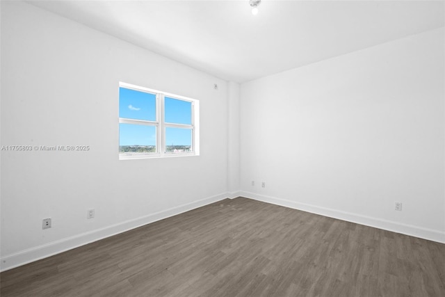 empty room featuring dark wood-style floors and baseboards