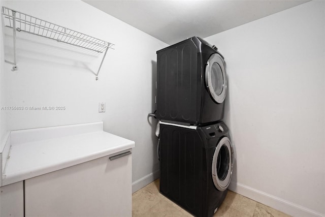 laundry room with laundry area, stacked washing maching and dryer, and baseboards