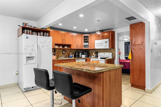 kitchen with light tile patterned floors, visible vents, white appliances, and tasteful backsplash