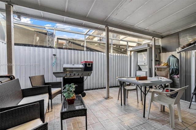 view of patio / terrace featuring glass enclosure, a grill, and fence