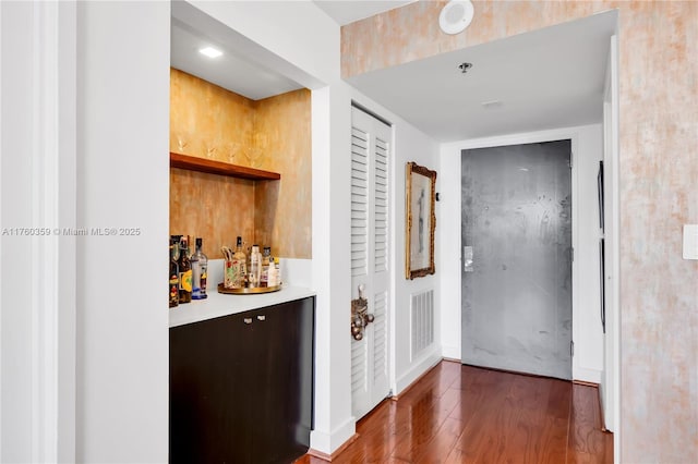 bar with visible vents, a dry bar, and wood finished floors