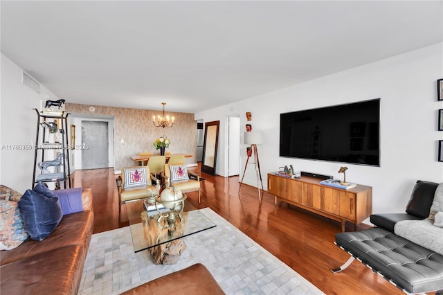 living room with visible vents, an inviting chandelier, and wood finished floors