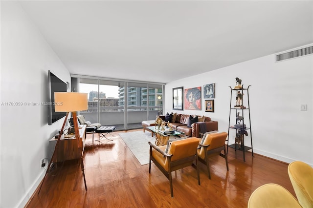 living area with visible vents, baseboards, and wood finished floors