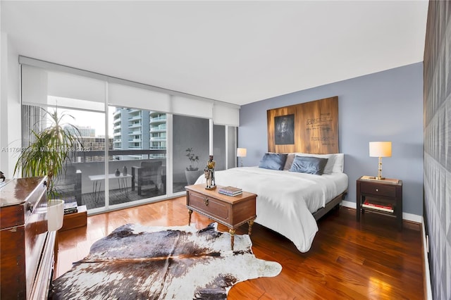 bedroom featuring access to exterior, a wall of windows, wood finished floors, and baseboards