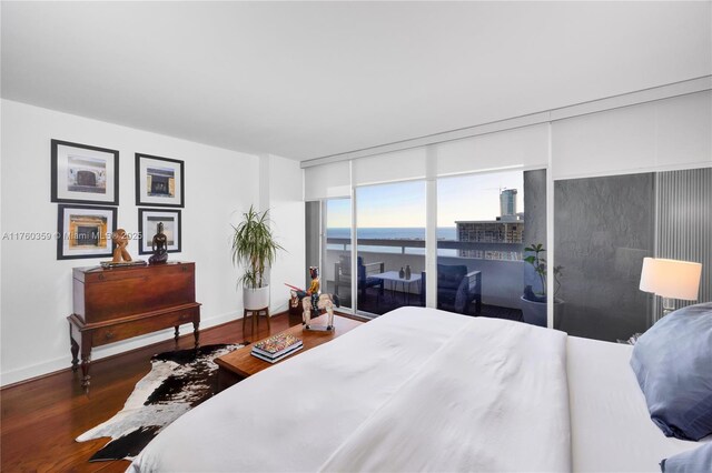 bedroom featuring wood finished floors, baseboards, and a water view