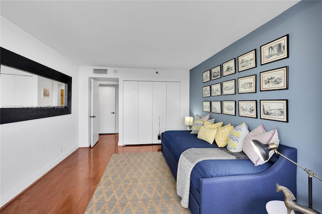 bedroom featuring a closet, visible vents, baseboards, and wood finished floors