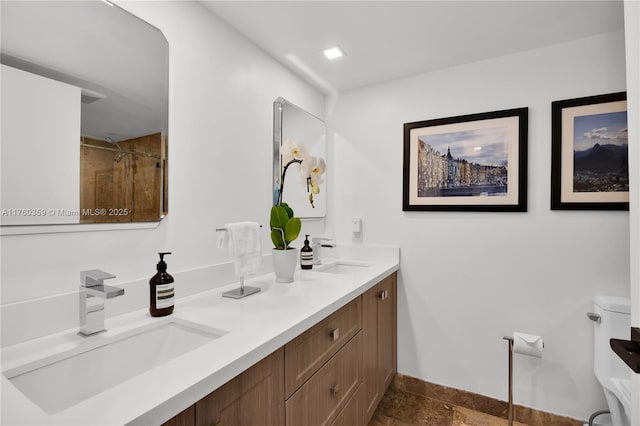 bathroom with toilet, double vanity, walk in shower, and a sink