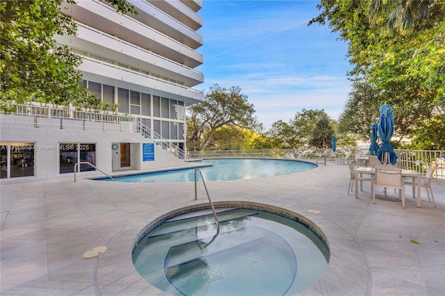 pool featuring stairway, a patio, and a community hot tub