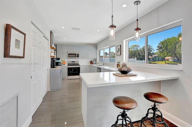 kitchen featuring visible vents, a sink, appliances with stainless steel finishes, a peninsula, and light countertops