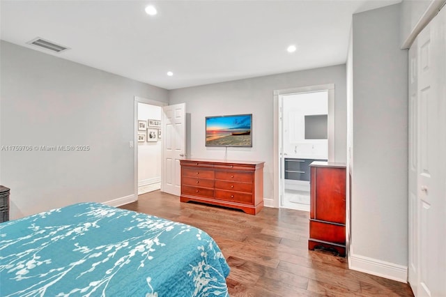 bedroom featuring visible vents, ensuite bath, wood finished floors, recessed lighting, and baseboards