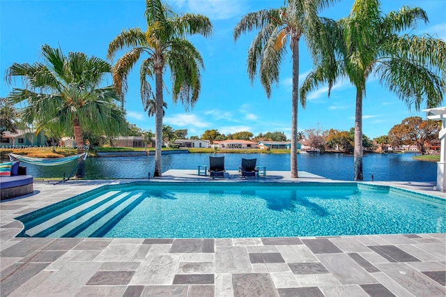 outdoor pool with a water view and a patio