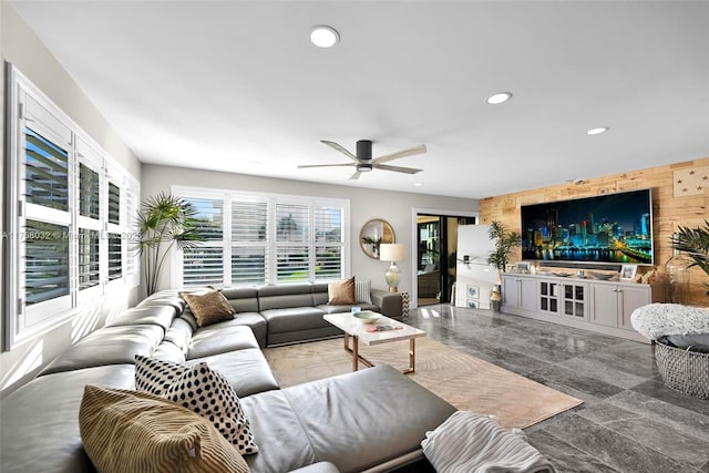 living room with wooden walls, recessed lighting, an accent wall, and ceiling fan