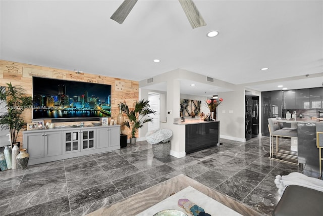 living area featuring visible vents, recessed lighting, wood walls, baseboards, and an accent wall