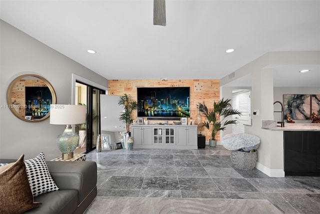 living area featuring an accent wall, wooden walls, recessed lighting, and visible vents