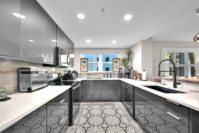 kitchen featuring stainless steel microwave, black electric range, modern cabinets, and a sink