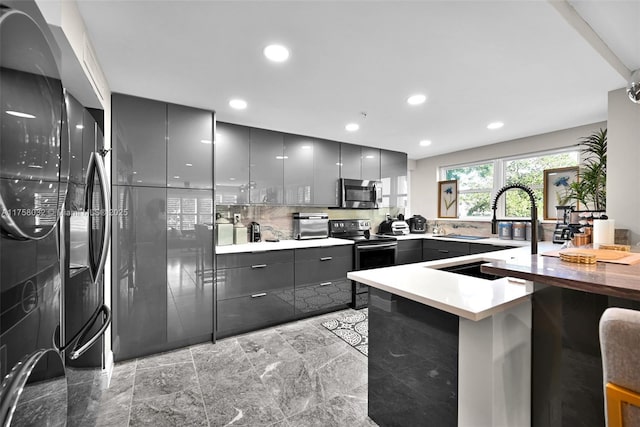 kitchen with stainless steel microwave, gray cabinetry, a peninsula, electric stove, and modern cabinets