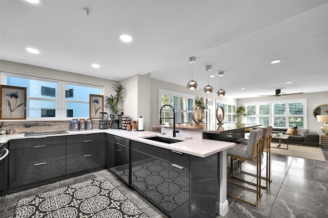 kitchen featuring light countertops, recessed lighting, a peninsula, modern cabinets, and a sink