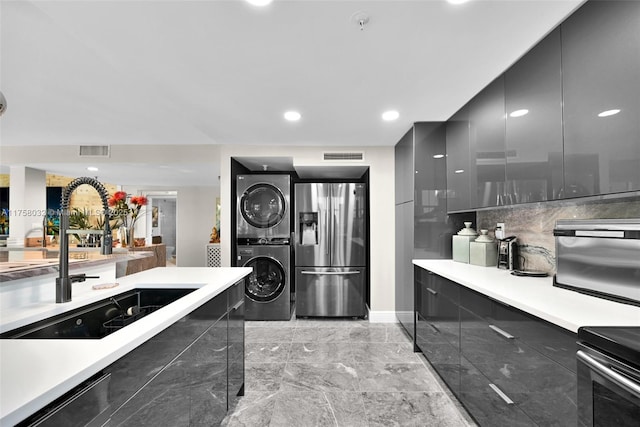 kitchen with visible vents, stainless steel fridge, dark cabinets, and stacked washing maching and dryer