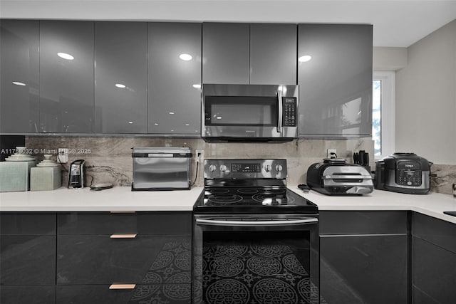 kitchen with stainless steel microwave, electric range, modern cabinets, and decorative backsplash