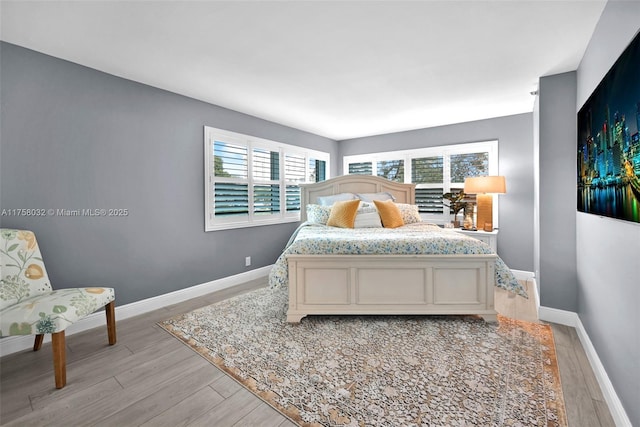 bedroom featuring multiple windows, light wood-style flooring, and baseboards