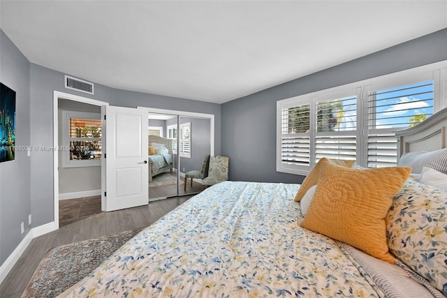 bedroom with a closet, visible vents, baseboards, and wood finished floors