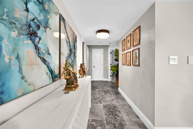 hallway with baseboards and stone finish flooring