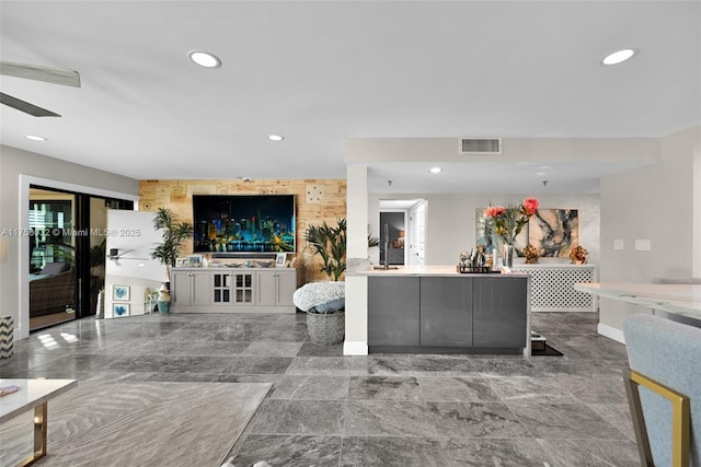 living area with recessed lighting, visible vents, and an accent wall