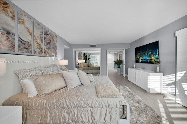 bedroom featuring visible vents, wood finished floors, multiple closets, and baseboards