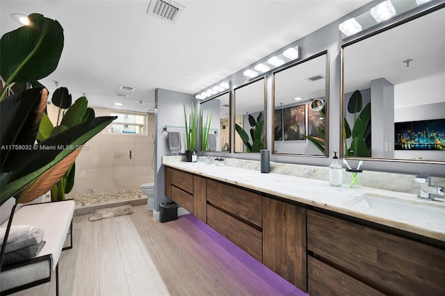 full bathroom with visible vents, a shower stall, toilet, double vanity, and a sink