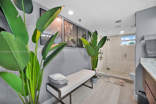 bathroom with visible vents, toilet, a stall shower, wood finished floors, and vanity