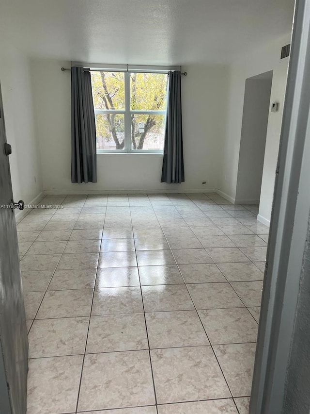 spare room featuring light tile patterned floors and baseboards