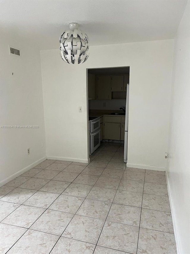 unfurnished dining area with visible vents, a sink, an inviting chandelier, light tile patterned floors, and baseboards