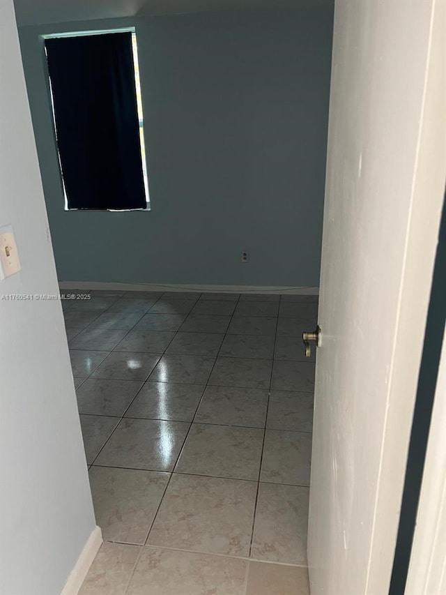 spare room with light tile patterned floors and baseboards