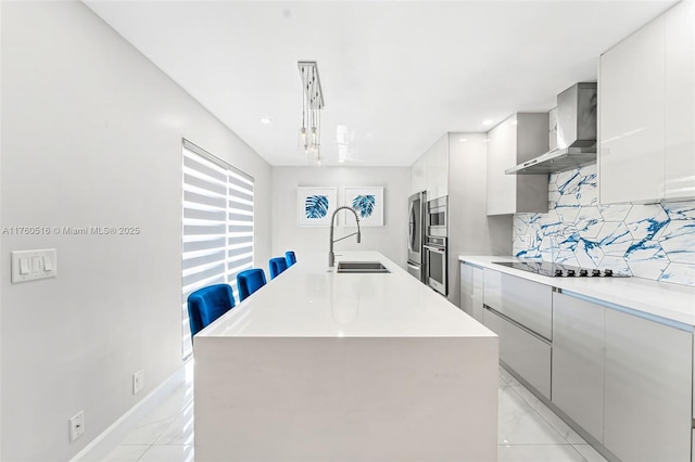 kitchen featuring wall chimney range hood, modern cabinets, backsplash, and a sink