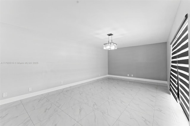 spare room featuring baseboards, marble finish floor, and a chandelier