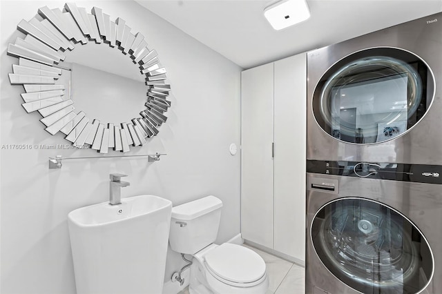 bathroom with a sink, toilet, and stacked washer and dryer