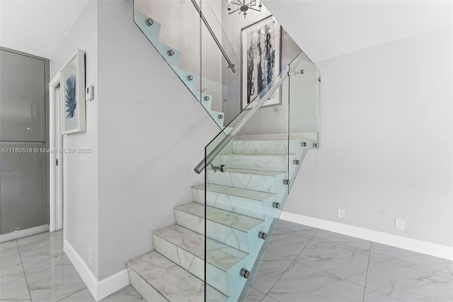 staircase featuring marble finish floor and baseboards