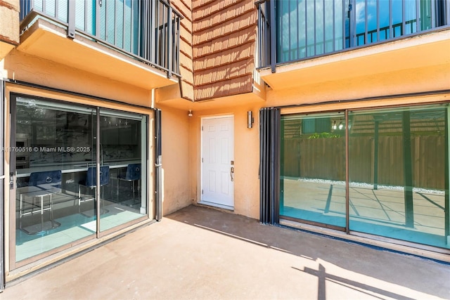 view of exterior entry featuring stucco siding and a balcony