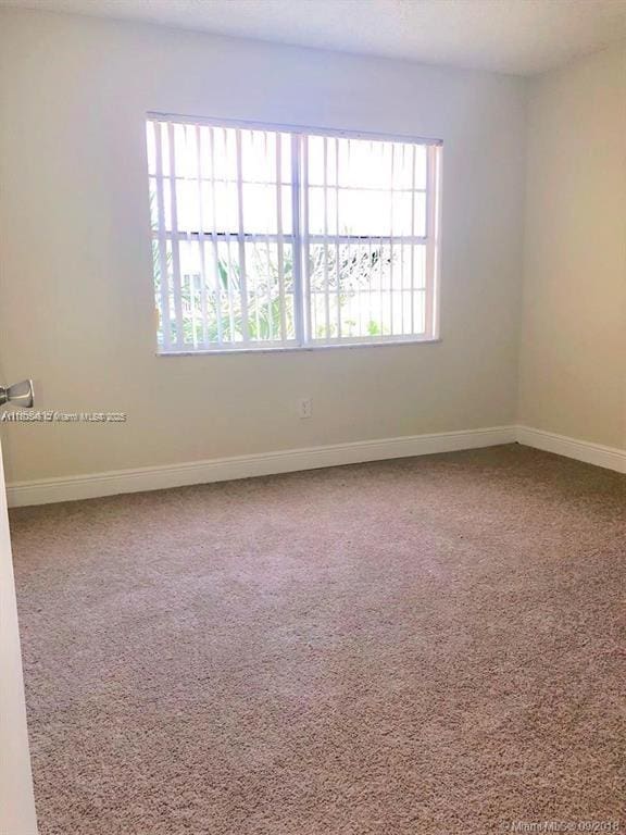 unfurnished room with baseboards and carpet