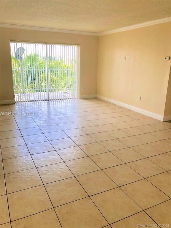 empty room with crown molding, light tile patterned flooring, baseboards, and a textured ceiling