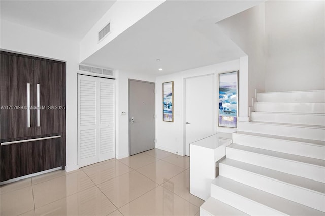 entryway with tile patterned flooring, stairs, and visible vents