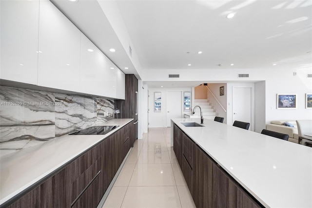 kitchen featuring a sink, black electric stovetop, modern cabinets, and white cabinets