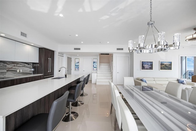 kitchen with a sink, light countertops, a kitchen breakfast bar, modern cabinets, and open floor plan