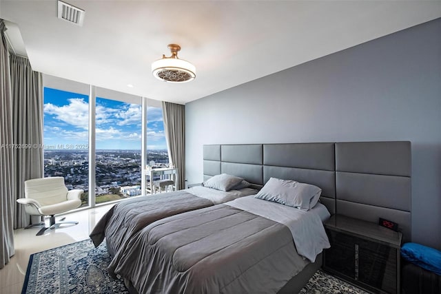 bedroom with visible vents, a view of city, and a wall of windows