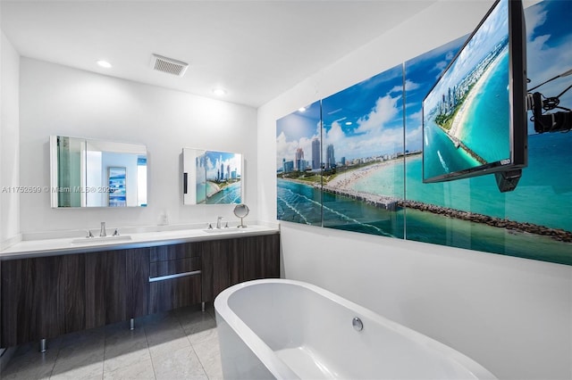 full bath featuring double vanity, a freestanding tub, visible vents, and a sink