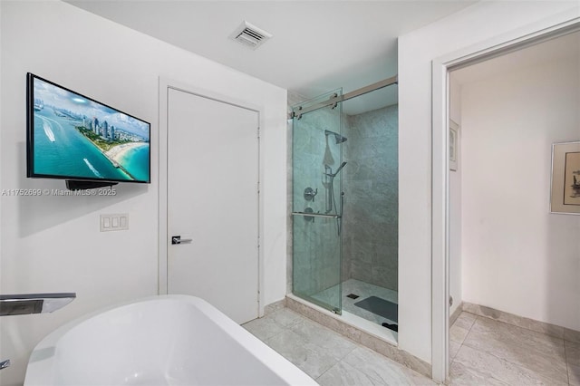 bathroom featuring visible vents, a stall shower, a freestanding bath, and baseboards