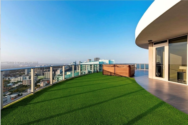 view of yard featuring a balcony, a city view, and a hot tub