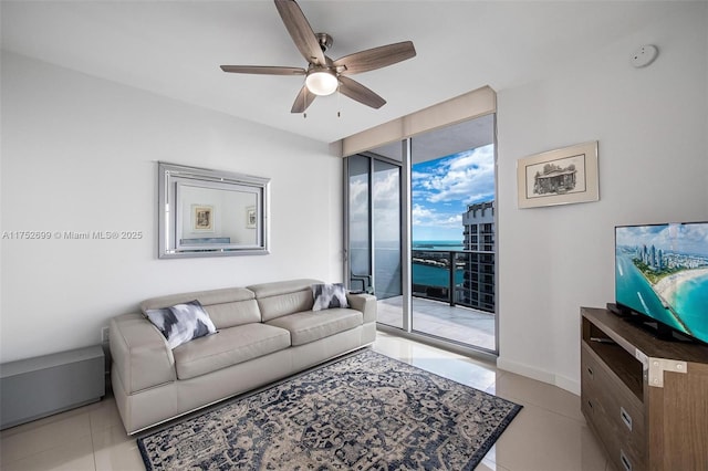 living area featuring floor to ceiling windows, light tile patterned floors, a ceiling fan, and baseboards