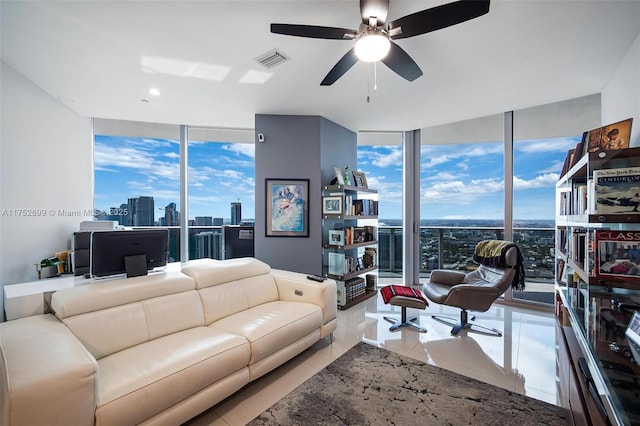 living room featuring tile patterned floors, expansive windows, visible vents, and ceiling fan